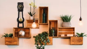 Horloge à poser design Comtoiselle en inox noir mise en situation dans un intérieur moderne avec étagères en bois et plantes.